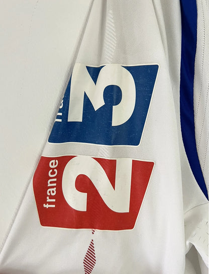 Maillot de foot vintage domicile blanc de l'OL de la saison 2007-2008. Il s'agit de l'édition coupe de france. On peut retrouver l'équipementier Umbro, ainsi que les sponsors SFR et Pitch. Le maillot est floqué du numéro 5 Mathieu Bodmer. Il s'agit d'un maillot authentique d'époque.