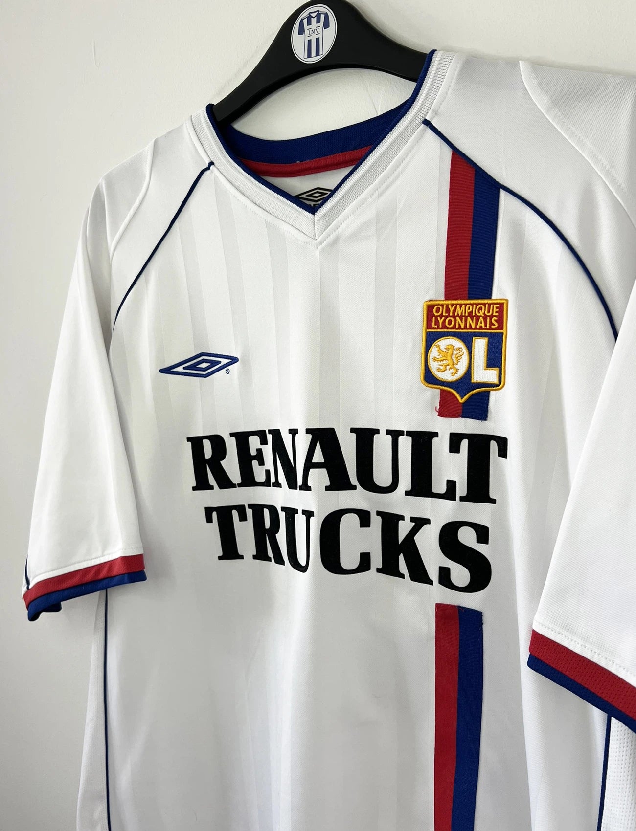 Maillot de foot vintage domicile de l'OL lors de la saison 2003/2004. Le maillot est de couleur blanc et bleu. On peut retrouver l'équipementier Umbro et le sponsor Renault Trucks. Le maillot est floqué du numéro 24 Vikash Dhorasoo. Il s'agit d'un maillot authentique