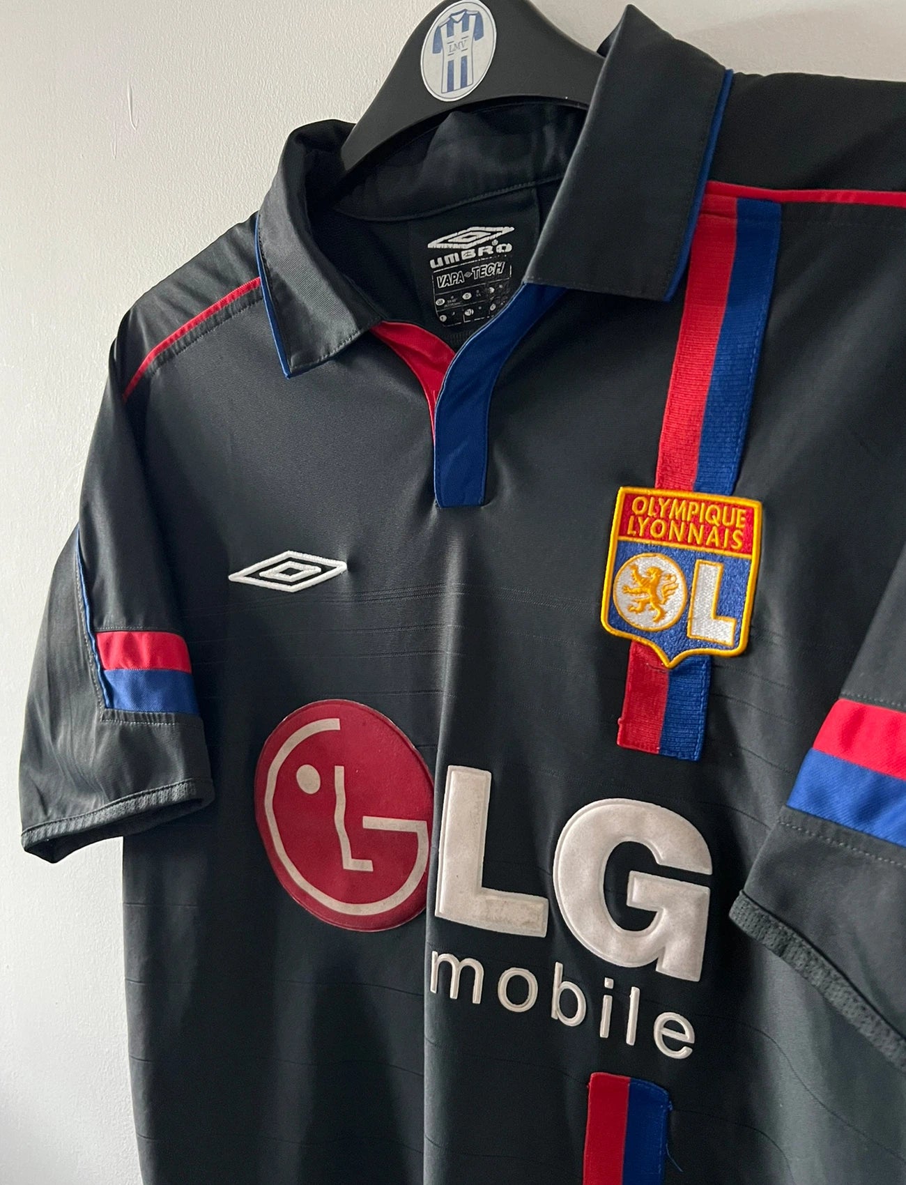 Maillot foot vintage extérieur noir de l'OL 2004/2005. On peut retrouver l'équipementier Umbro et le sponsor LG. Il s'agit d'un maillot authentique d'époque.