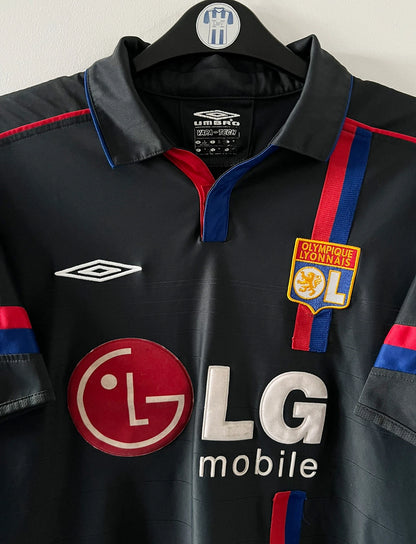 Maillot foot vintage extérieur noir de l'OL 2004/2005. On peut retrouver l'équipementier Umbro et le sponsor LG. Il s'agit d'un maillot authentique d'époque.