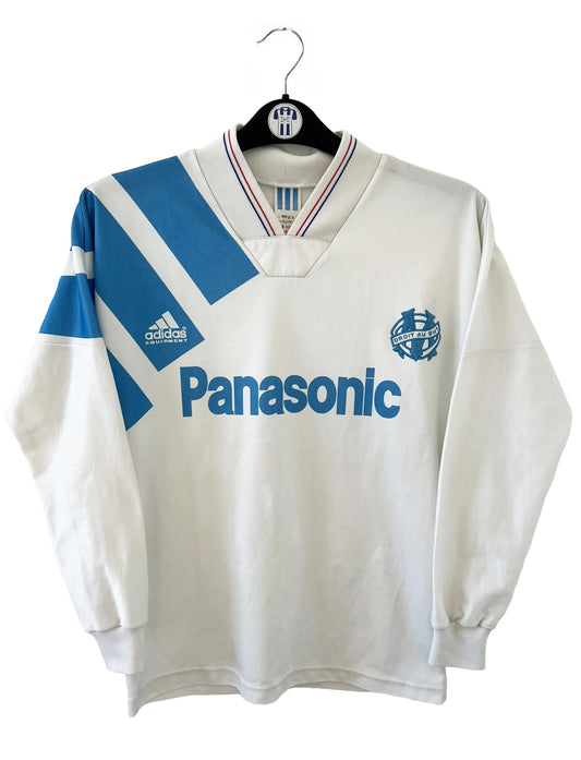 Maillot de foot vintage de l'OM de la saison 1991/1992. Il s'agit du maillot domicile blanc et bleu. On peut retrouver l'équipementier adidas et le sponsor panasonic. Il s'agit d'un maillot authentique d'époque.