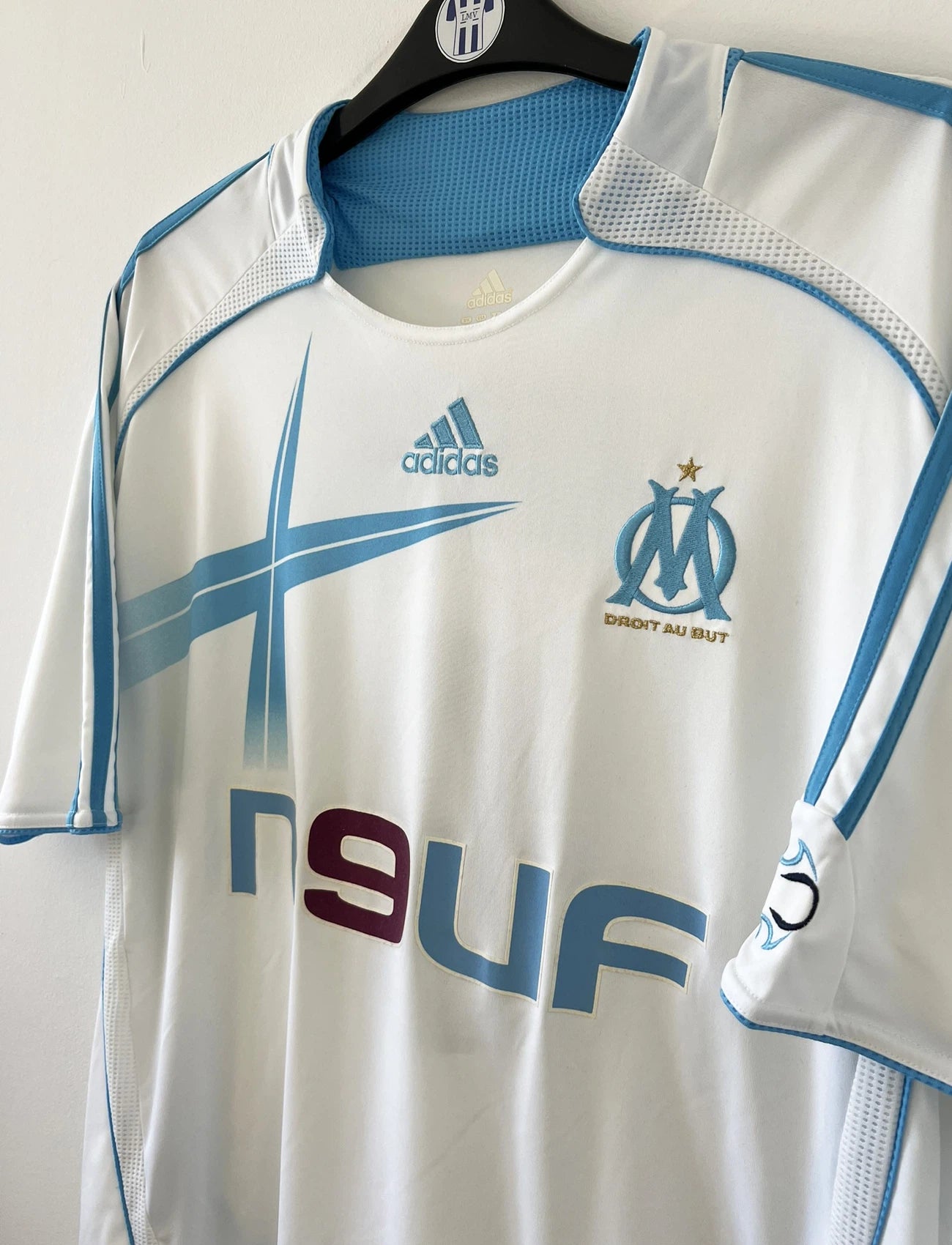 Maillot de foot vintage domicile de l'OM de la saison 2006/2007. Le maillot est de couleur blanc et bleu. On peut retrouver l'équipementier adidas et le sponsor Neuf. Le maillot est floqué du numéro 9 Djibril Cissé. Il s'agit d'un maillot authentique d'époque comportant les numéros 084929