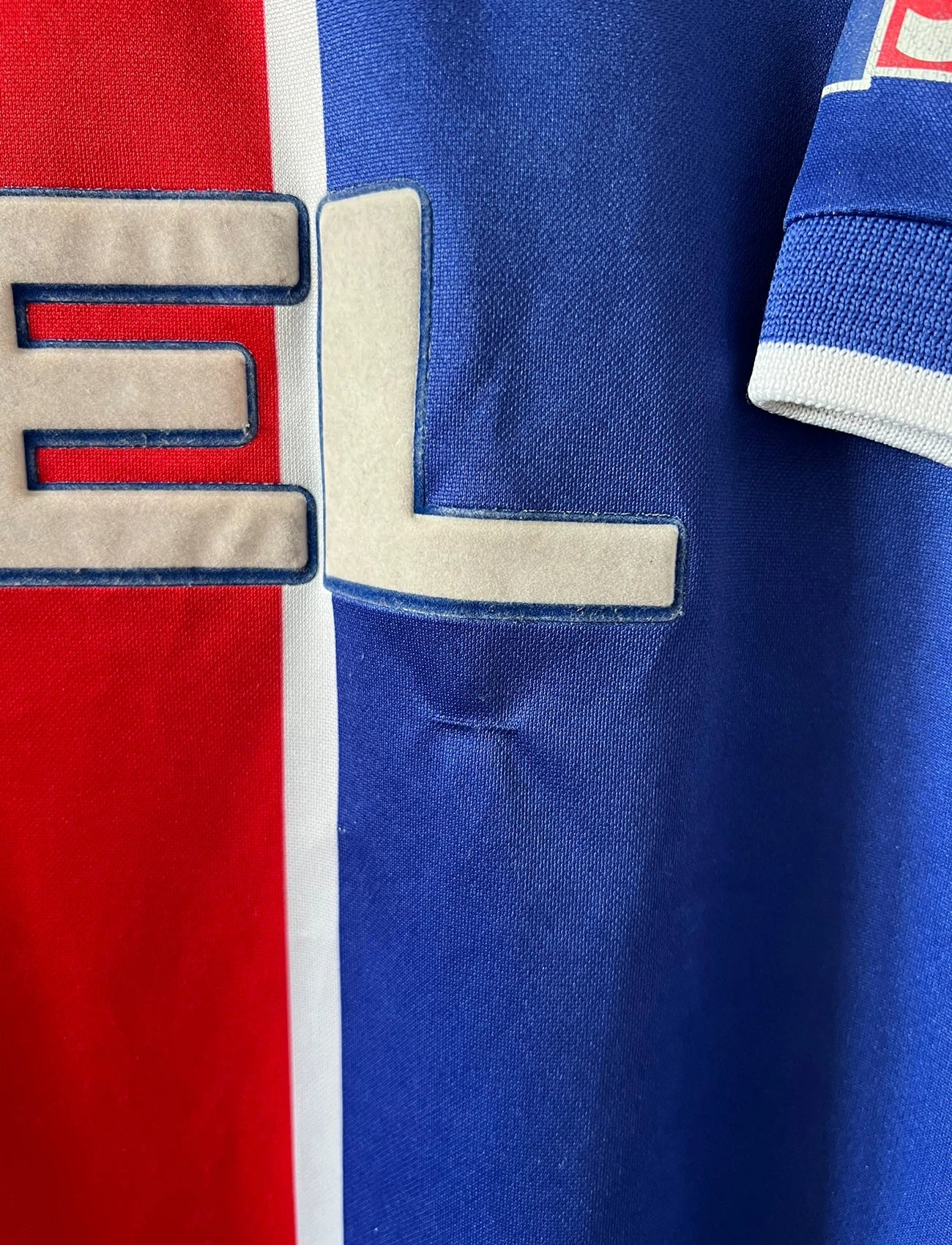 Maillot de foot vintage domicile rouge et bleu du PSG 1999/2000. On peut retrouver l'équipementier Nike et le sponsor Opel. Il s'agit d'un maillot authentique d'époque.