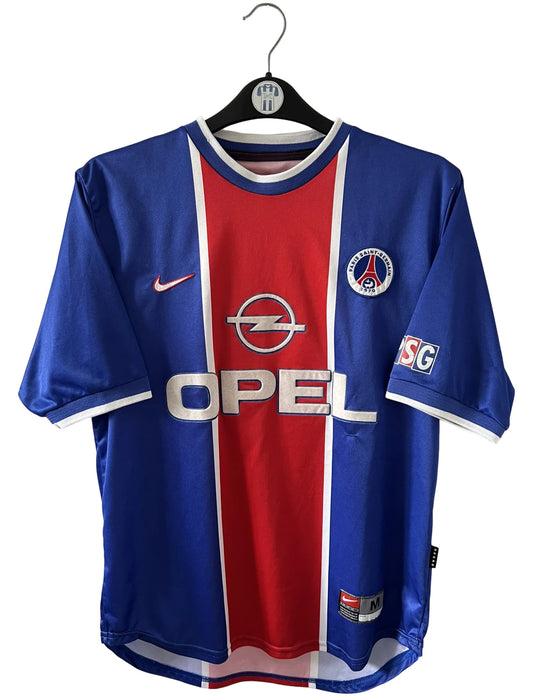 Maillot de foot vintage domicile rouge et bleu du PSG 1999/2000. On peut retrouver l'équipementier Nike et le sponsor Opel. Il s'agit d'un maillot authentique d'époque.