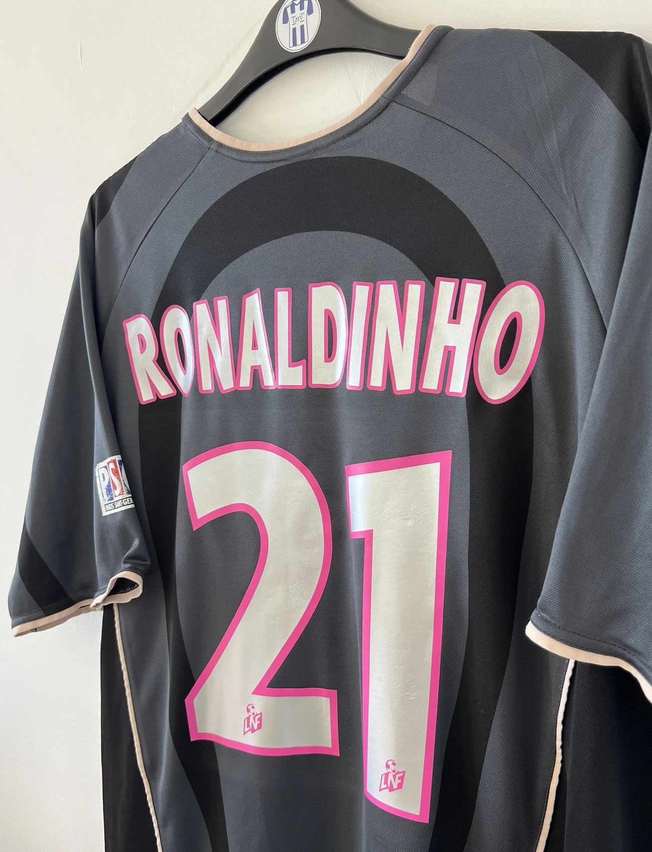 Maillot de foot vintage third du PSG de la saison 2001/2002. Le maillot est de couleur noir et gris. On peut retrouver l'équipementier nike et le sponsor Opel. Le maillot est floqué du numéro 21 Ronaldinho. Le maillot possède l'étiquette avec les numéros F1 ORX. Il s'agit d'un maillot authentique d'époque.