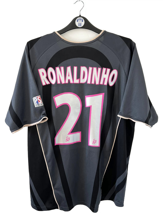 Maillot de foot vintage third du PSG de la saison 2001/2002. Le maillot est de couleur noir et gris. On peut retrouver l'équipementier nike et le sponsor Opel. Le maillot est floqué du numéro 21 Ronaldinho. Le maillot possède l'étiquette avec les numéros F1 ORX. Il s'agit d'un maillot authentique d'époque.