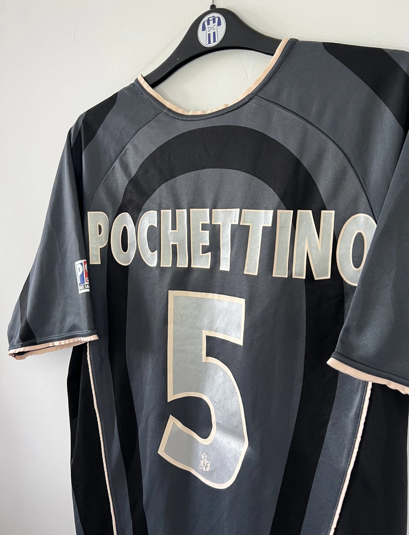 Maillot de foot vintage third du PSG 2001/2002. Le maillot est de couleur noir et gris. On peut retrouver l'équipementier nike et le sponsor Opel. Le maillot est floqué du numéro 5 Pochettino. Il s'agit d'un maillot authentique avec l'étiquette et les numéros F1AOG