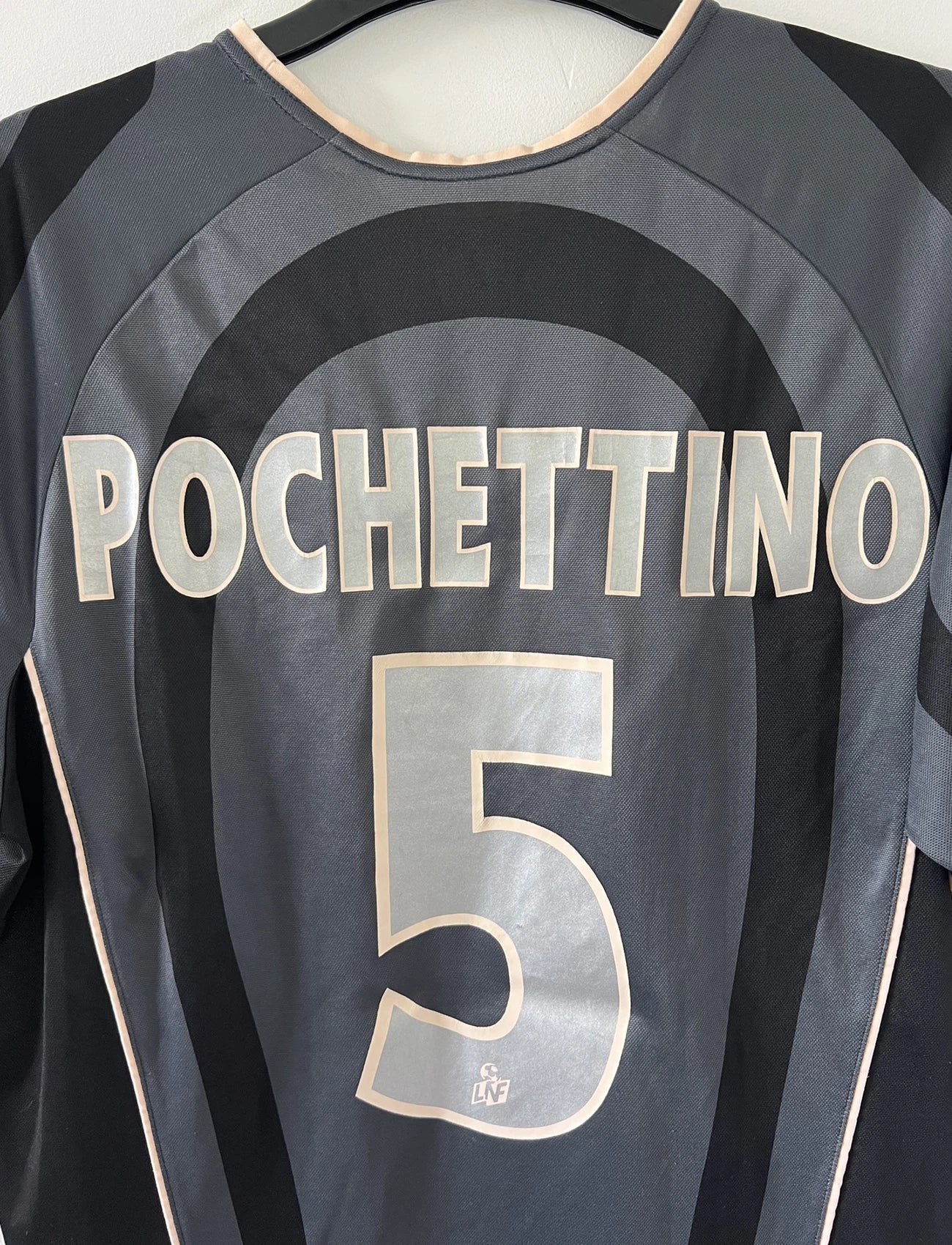 Maillot de foot vintage third du PSG 2001/2002. Le maillot est de couleur noir et gris. On peut retrouver l'équipementier nike et le sponsor Opel. Le maillot est floqué du numéro 5 Pochettino. Il s'agit d'un maillot authentique avec l'étiquette et les numéros F1AOG