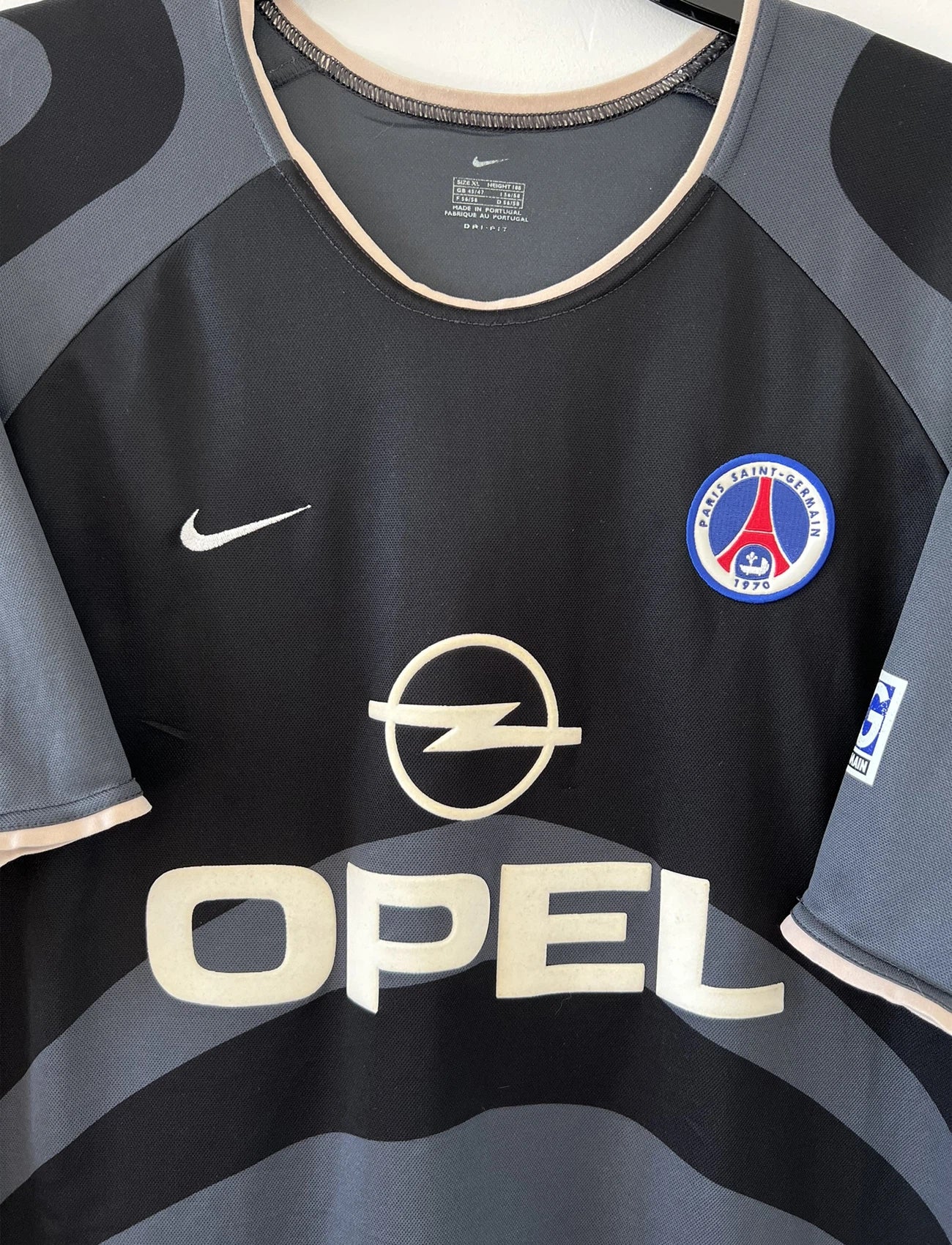 Maillot de foot vintage third du PSG de la saison 2001/2002. Le maillot est de couleur noir et gris. On peut retrouver l'équipementier nike et le sponsor Opel. Le maillot est floqué du numéro 21 Ronaldinho. Le maillot possède l'étiquette avec les numéros F1 ORX. Il s'agit d'un maillot authentique d'époque.