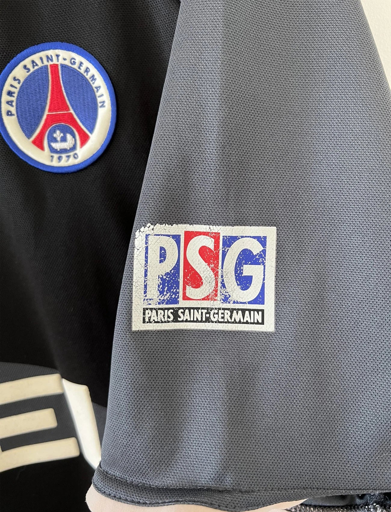 Maillot de foot vintage third du PSG de la saison 2001/2002. Le maillot est de couleur noir et gris. On peut retrouver l'équipementier nike et le sponsor Opel. Le maillot est floqué du numéro 21 Ronaldinho. Le maillot possède l'étiquette avec les numéros F1 ORX. Il s'agit d'un maillot authentique d'époque.