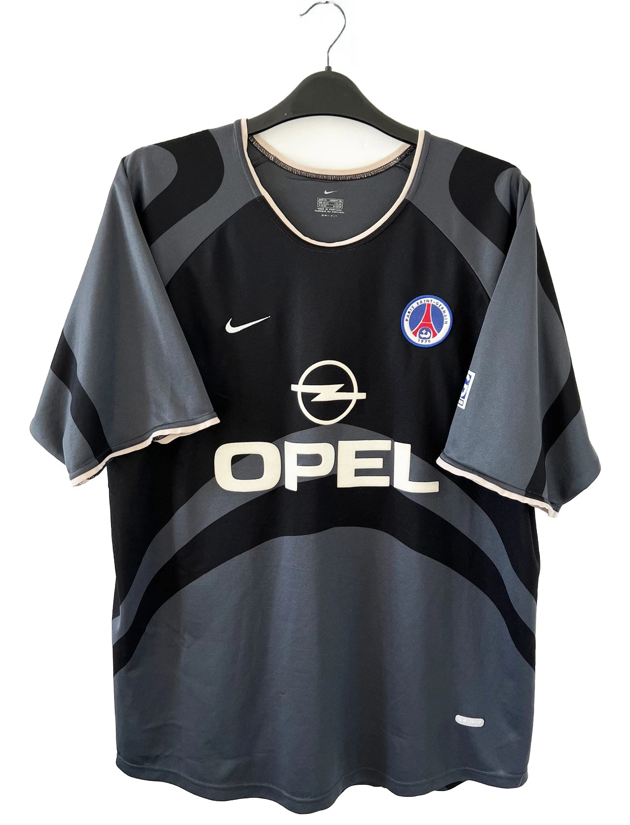 Maillot de foot vintage third du PSG de la saison 2001/2002. Le maillot est de couleur noir et gris. On peut retrouver l'équipementier nike et le sponsor Opel. Le maillot est floqué du numéro 21 Ronaldinho. Le maillot possède l'étiquette avec les numéros F1 ORX. Il s'agit d'un maillot authentique d'époque.