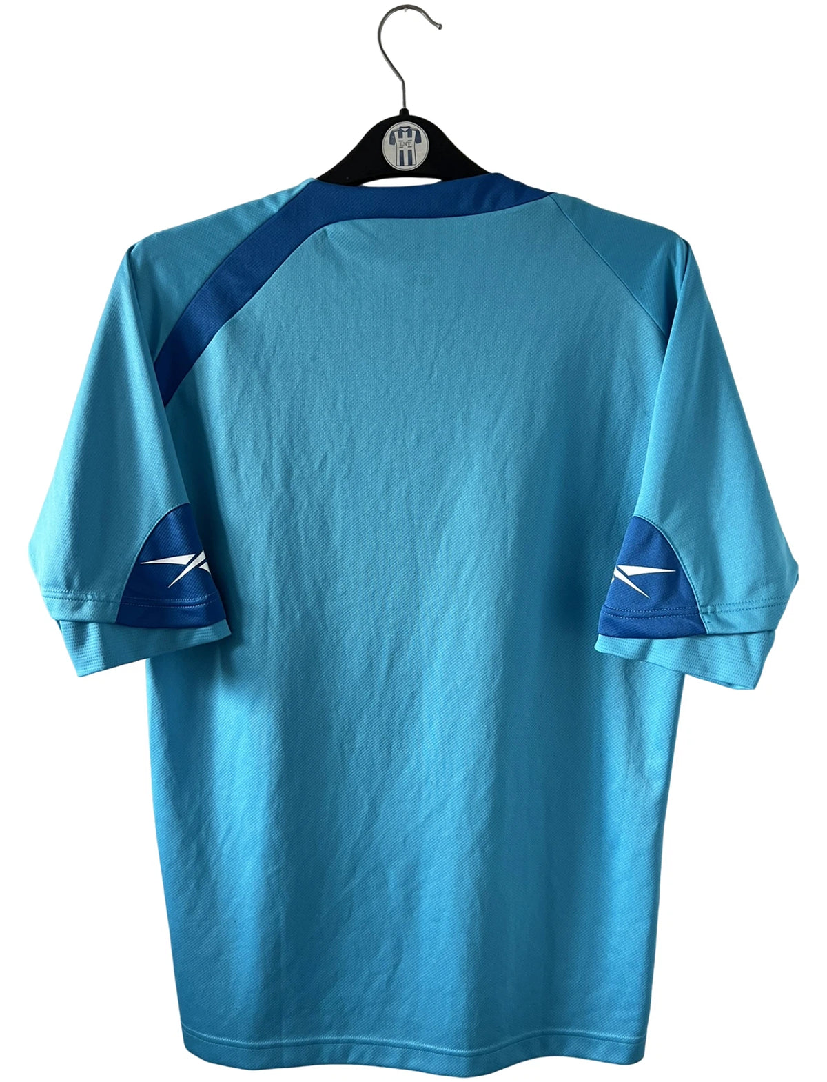 Maillot de foot vintage extérieur bleu du RC Lens 2009/2010. On peut retrouver l'équipementier Reebok et le sponsor Invicta. Il s'agit d'un maillot authentique d'époque.
