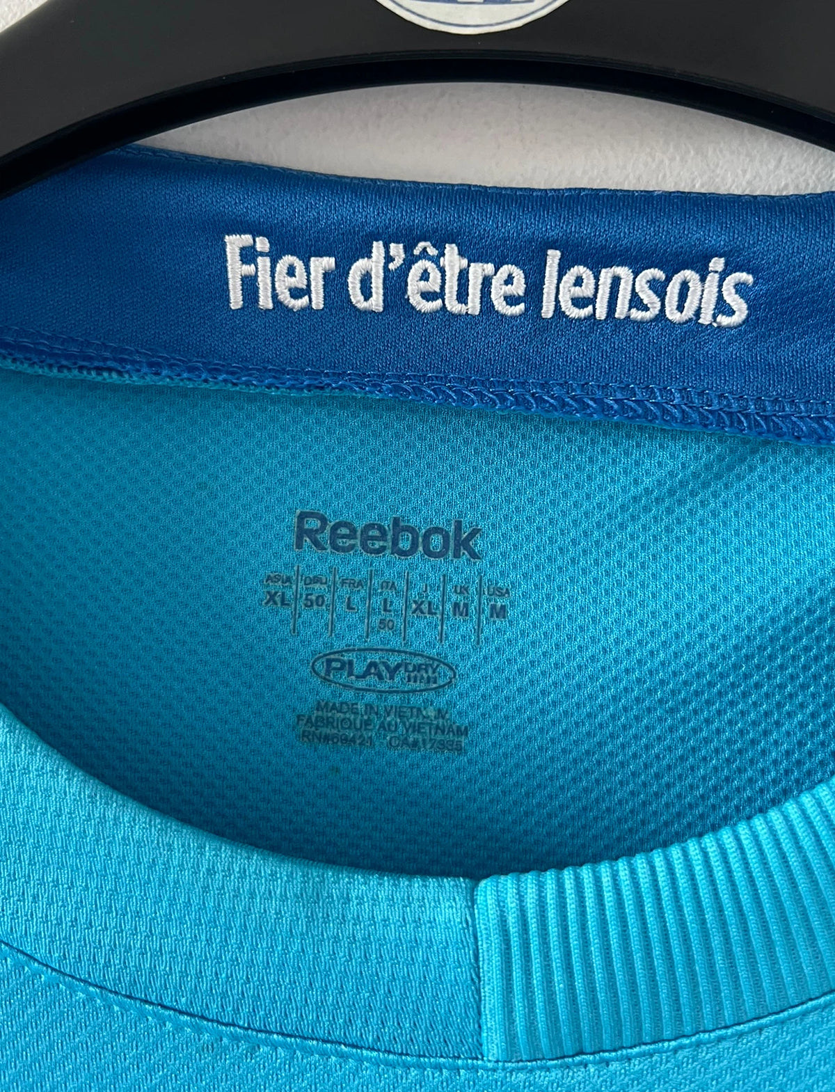 Maillot de foot vintage extérieur bleu du RC Lens 2009/2010. On peut retrouver l'équipementier Reebok et le sponsor Invicta. Il s'agit d'un maillot authentique d'époque.
