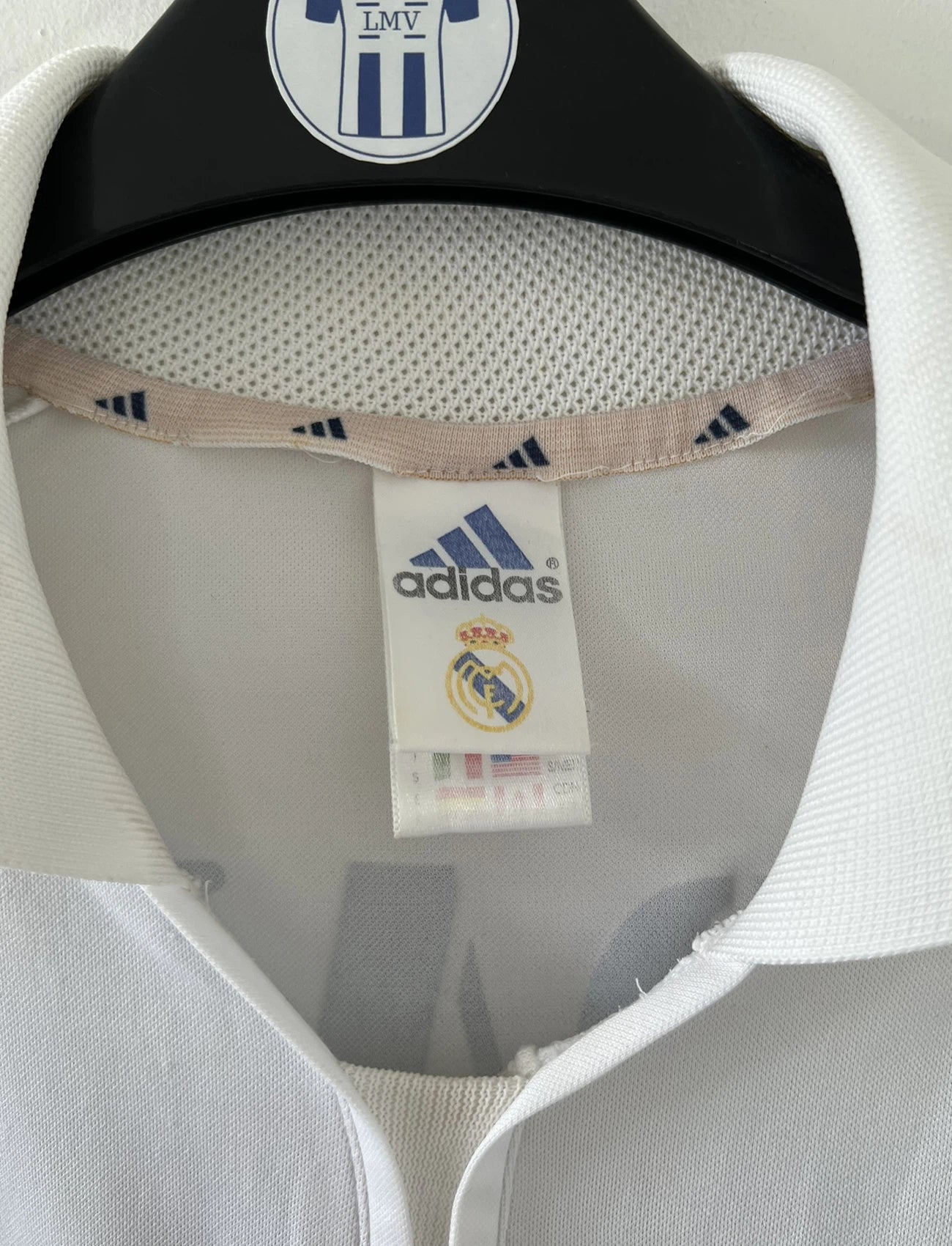 Maillot de foot vintage domicile du real madrid de la saison 2001-2002. Le maillot est de couleur blanc et noir. On peut retrouver l'équipementier adidas et le sponsor Real Madrid.com. Le maillot est floqué du numéro 5 Zinedine Zidane. Il s'agit d'un maillot authentique