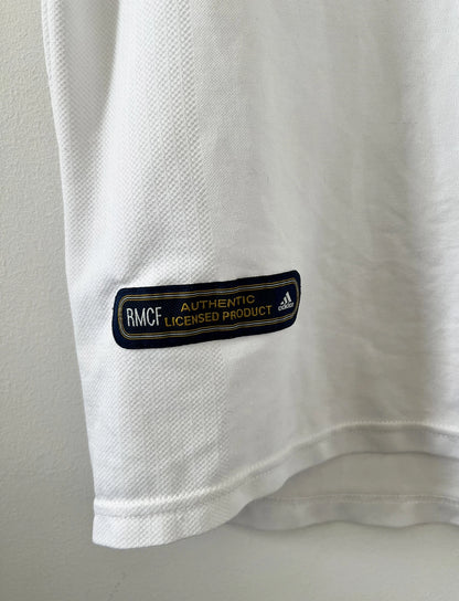 Maillot de foot vintage domicile du real madrid de la saison 2001-2002. Le maillot est de couleur blanc et noir. On peut retrouver l'équipementier adidas et le sponsor Real Madrid.com. Le maillot est floqué du numéro 5 Zinedine Zidane. Il s'agit d'un maillot authentique