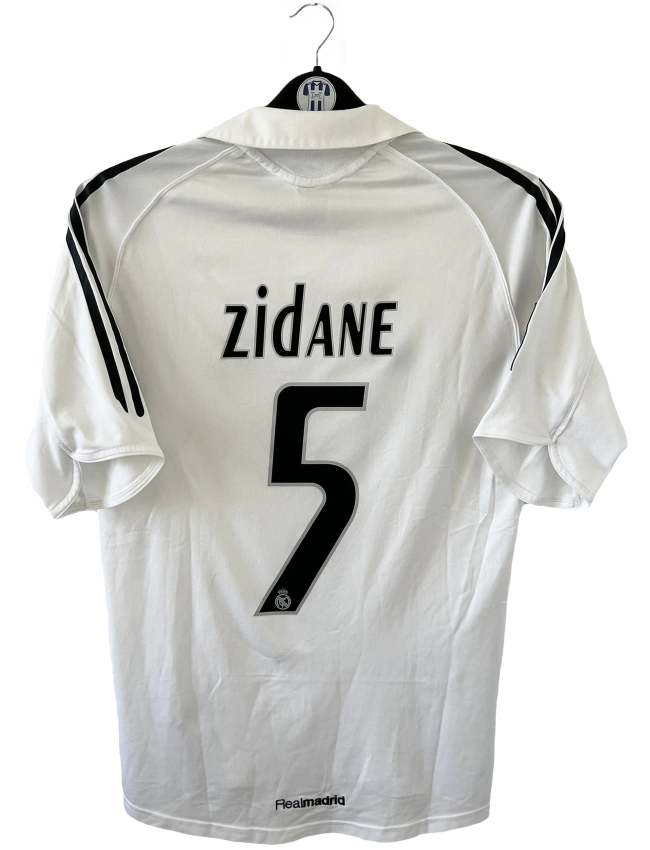 Maillot de foot vintage domicile du Real Madrid de la saison 2005/2006. Le maillot est de couleur blanc et noir. On peut retrouver l'équipementier adidas et le sponsor siemens. Le maillot est floqué du numéro 5 Zinedine Zidane. Le maillot possède l'étiquette d'authenticité avec les numéros 109879. Il s'agit d'un maillot authentique d'époque.