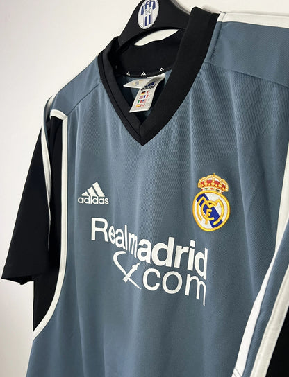 Maillot de foot vintage third gris du real madrid de la saison 2001-2002. On peut retrouver l'équipementier Adidas et le sponsor RealMadrid.com. Le maillot est floqué du numéro 5 Zinedine Zidane. Il s'agit d'un maillot authentique d'époque.