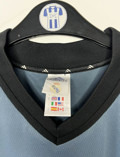 Maillot de foot vintage third gris du real madrid de la saison 2001-2002. On peut retrouver l'équipementier Adidas et le sponsor RealMadrid.com. Le maillot est floqué du numéro 5 Zinedine Zidane. Il s'agit d'un maillot authentique d'époque.