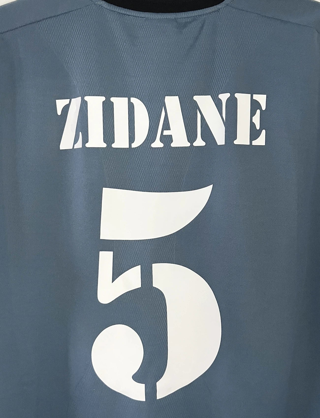 Maillot de foot vintage third gris du real madrid de la saison 2001-2002. On peut retrouver l'équipementier Adidas et le sponsor RealMadrid.com. Le maillot est floqué du numéro 5 Zinedine Zidane. Il s'agit d'un maillot authentique d'époque.