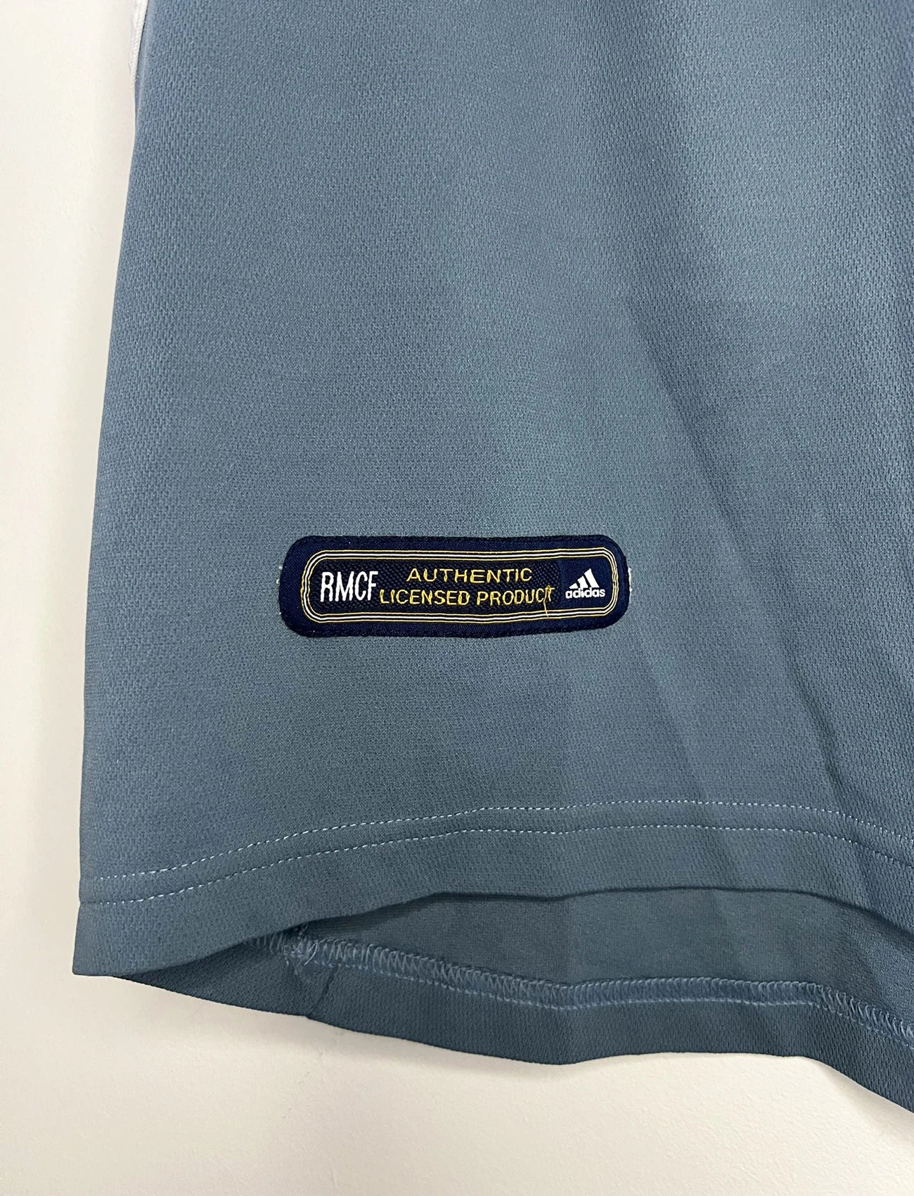 Maillot de foot vintage third gris du real madrid de la saison 2001-2002. On peut retrouver l'équipementier Adidas et le sponsor RealMadrid.com. Le maillot est floqué du numéro 5 Zinedine Zidane. Il s'agit d'un maillot authentique d'époque.