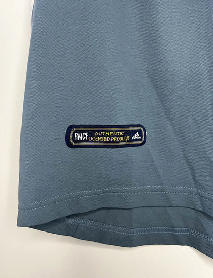 Maillot de foot vintage third gris du real madrid de la saison 2001-2002. On peut retrouver l'équipementier Adidas et le sponsor RealMadrid.com. Le maillot est floqué du numéro 5 Zinedine Zidane. Il s'agit d'un maillot authentique d'époque.