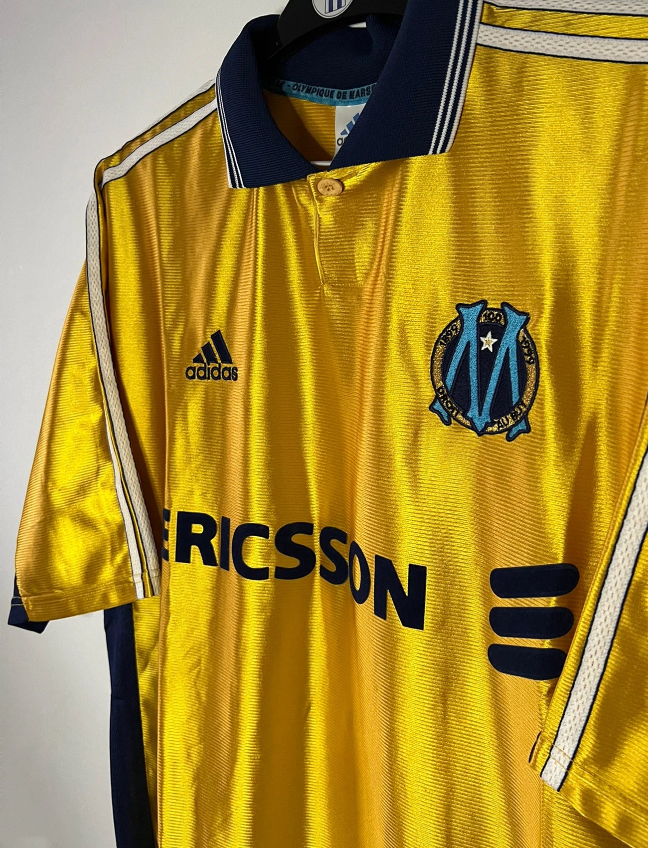Maillot de foot vintage third doré de l'OM de la saison 1998/1999. On peut retrouver l'équipementier Adidas et le sponsor Ericsson. Il s'agit d'un maillot authentique d'époque.
