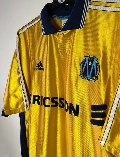 Maillot de foot vintage third doré de l'OM de la saison 1998/1999. On peut retrouver l'équipementier Adidas et le sponsor Ericsson. Il s'agit d'un maillot authentique d'époque.