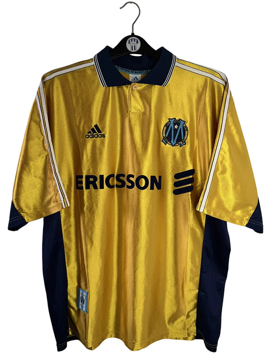 Maillot de foot vintage third doré de l'OM de la saison 1998/1999. On peut retrouver l'équipementier Adidas et le sponsor Ericsson. Il s'agit d'un maillot authentique d'époque.