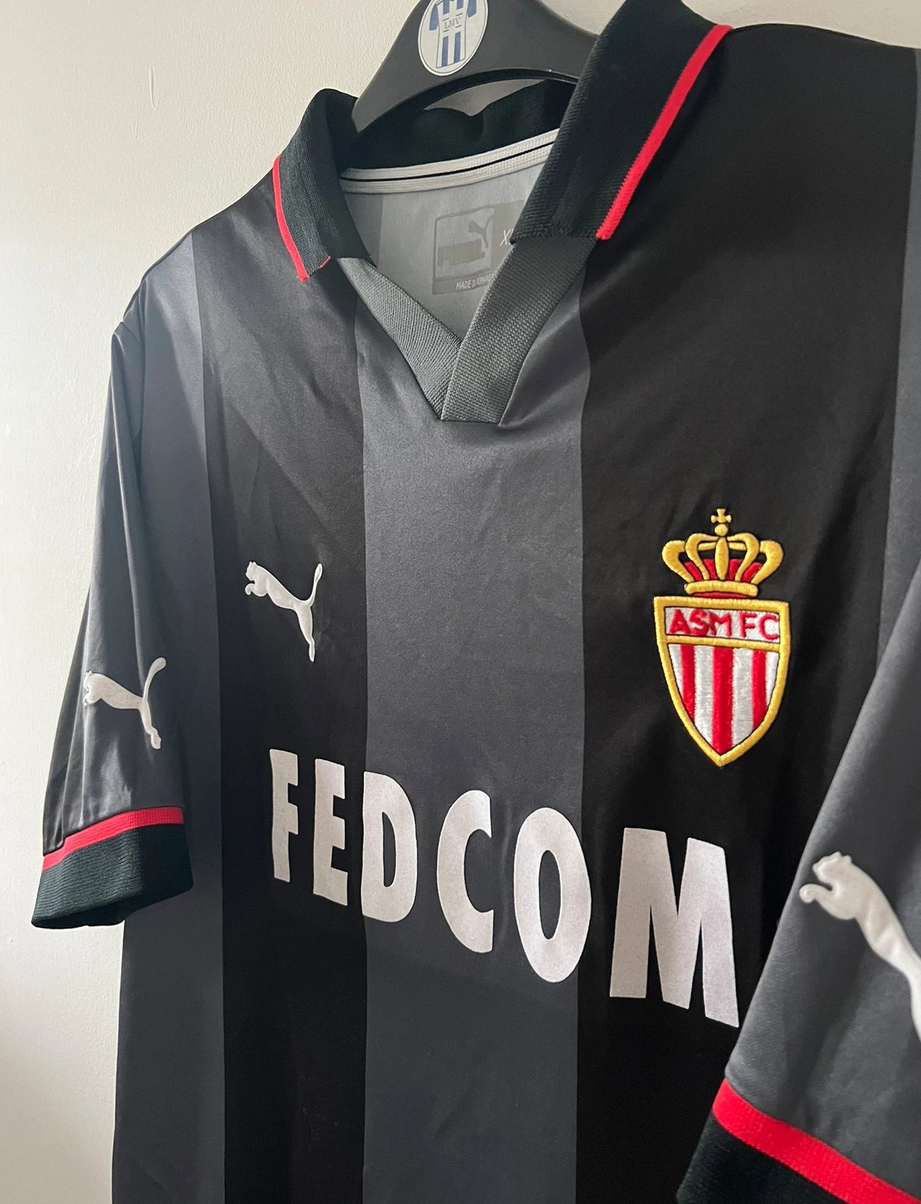 Maillot de foot vintage extérieur noir de l'AS Monaco saison 2002-2003. On peut retrouver l'équipementier Puma et le sponsor Fedcom. Il s'agit d'un maillot authentique d'époque.