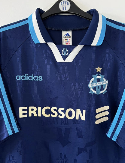Maillot de foot vintage third bleu de l'om 1997/1998. On peut retrouver l'équipementier Adidas et le sponsor Ericsson. Il s'agit d'un maillot authentique d'époque.