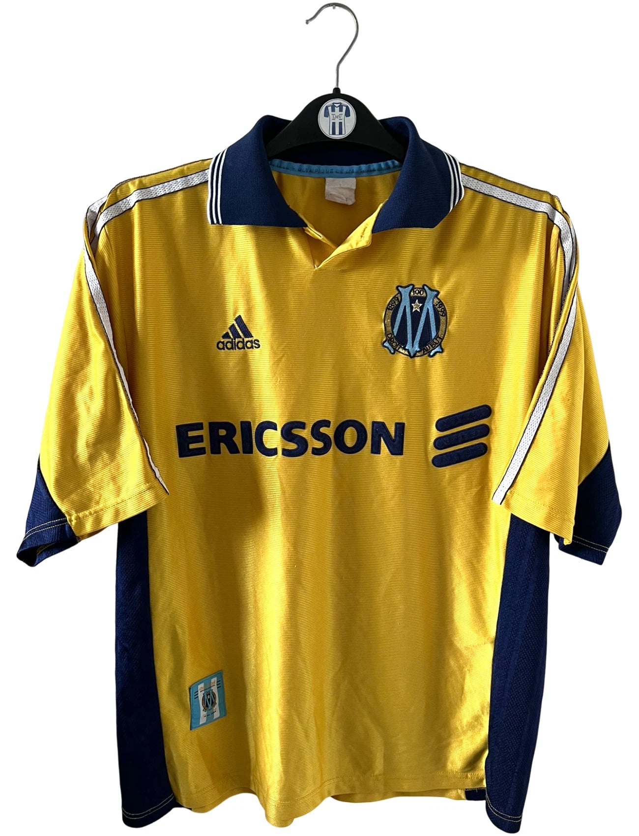 Maillot de foot vintage third doré de l'OM saison 1998/1999. On peut retrouver l'équipementier Adidas et le sponsor Ericsson. Il s'agit d'un maillot authentique d'époque.