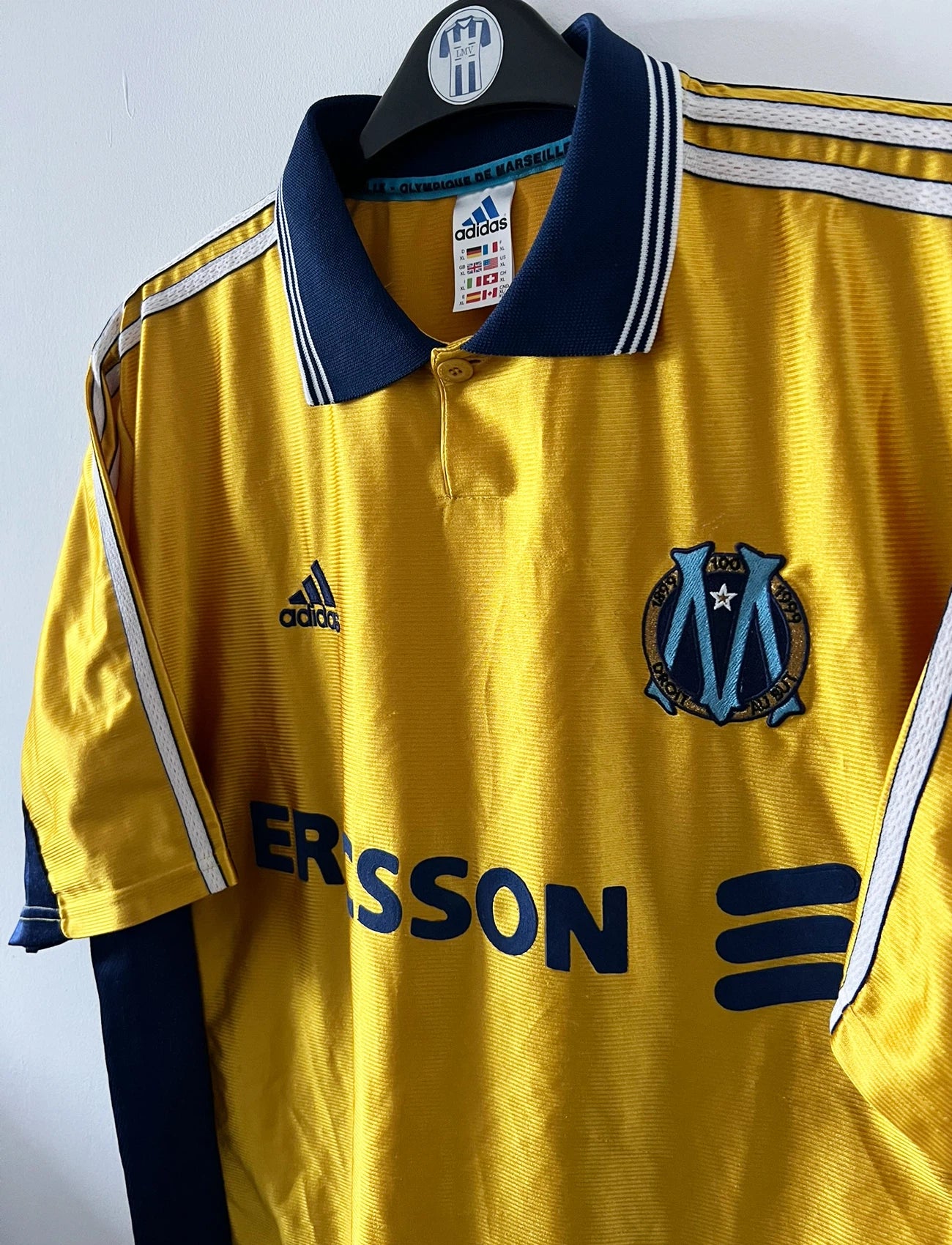 Maillot + short vintage third doré de l'OM 1998-1999. On peut retrouver l'équipementier Adidas et le sponsor Ericsson. Il s'agit d'un maillot et d'un short authentique d'époque.
