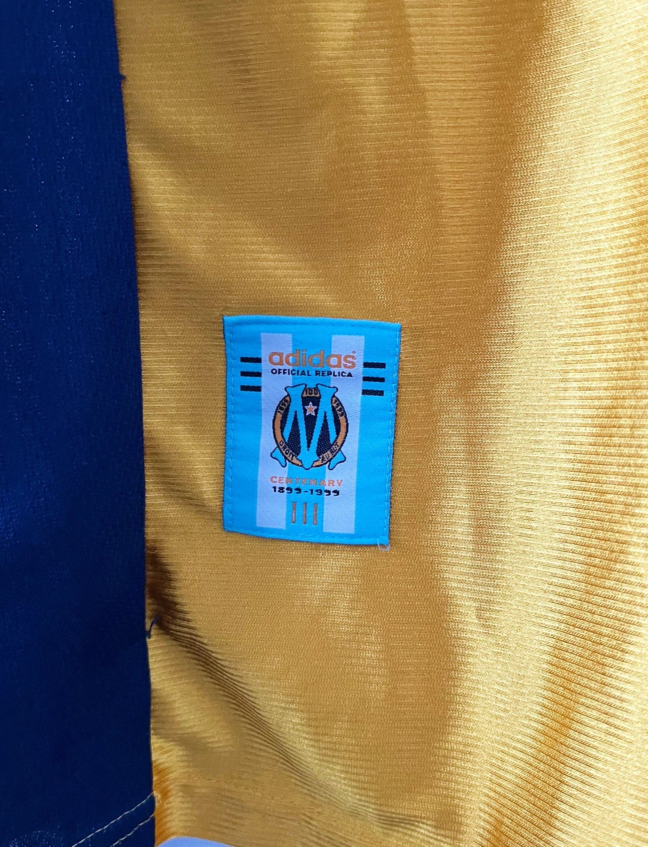 Maillot + short vintage third doré de l'OM 1998-1999. On peut retrouver l'équipementier Adidas et le sponsor Ericsson. Il s'agit d'un maillot et d'un short authentique d'époque.