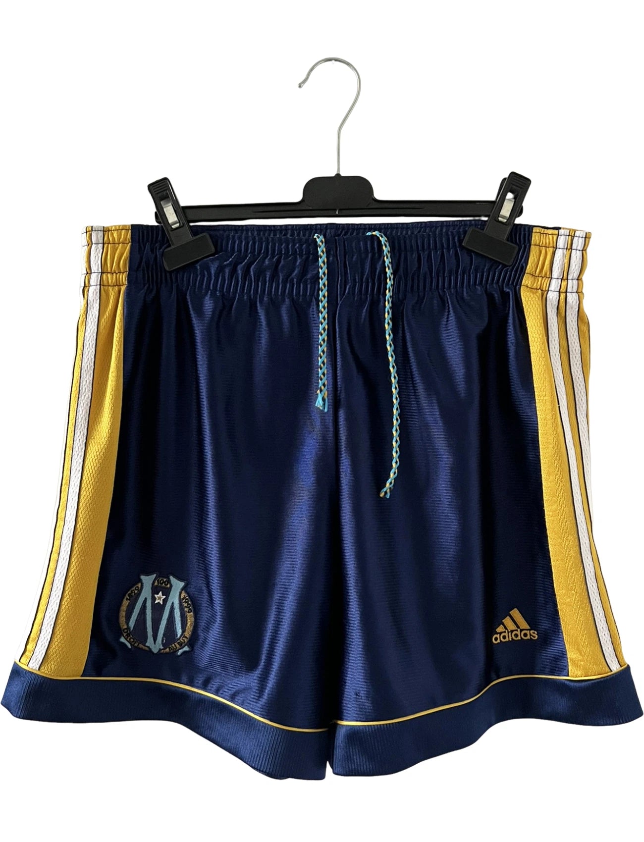Maillot + short vintage third doré de l'OM 1998-1999. On peut retrouver l'équipementier Adidas et le sponsor Ericsson. Il s'agit d'un maillot et d'un short authentique d'époque.