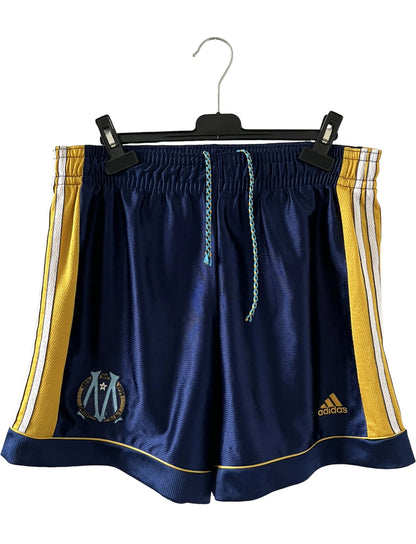 Maillot + short vintage third doré de l'OM 1998-1999. On peut retrouver l'équipementier Adidas et le sponsor Ericsson. Il s'agit d'un maillot et d'un short authentique d'époque.