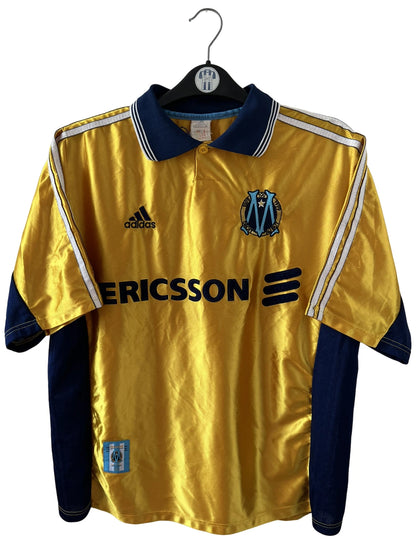 Maillot de foot vintage third doré de l'OM 1998/1999. On peut retrouver l'équipementier Adidas et le sponsor Ericsson. Il s'agit d'un maillot authentique d'époque.