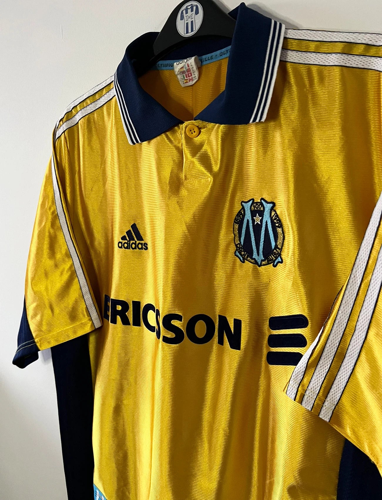 Maillot de foot vintage third doré de l'om 1998/1999. On peut retrouver l'équipementier Adidas et le sponsor Ericsson. Il s'agit d'un maillot authentique d'époque.