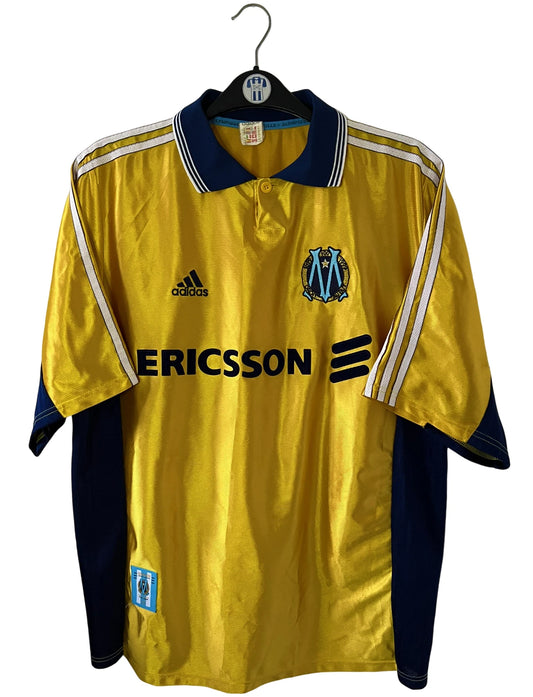Maillot de foot vintage third doré de l'om 1998/1999. On peut retrouver l'équipementier Adidas et le sponsor Ericsson. Il s'agit d'un maillot authentique d'époque.