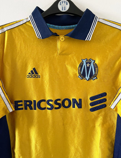 Maillot de foot vintage third doré de l'OM 1998/1999. On peut retrouver l'équipementier Adidas et le sponsor Ericsson. Il s'agit d'un maillot authentique d'époque.