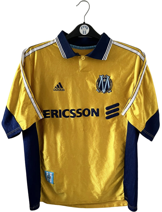 Maillot de foot vintage third doré de l'OM 1998/1999. On peut retrouver l'équipementier Adidas et le sponsor Ericsson. Il s'agit d'un maillot authentique d'époque.