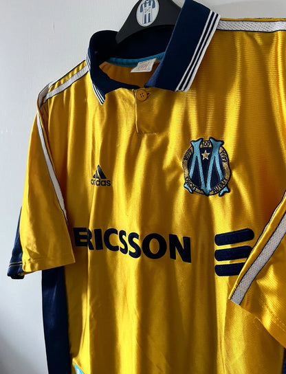 Maillot de foot vintage third doré de l'om 1998/1999. On peut retrouver l'équipementier Adidas et le sponsor Ericsson. Il s'agit d'un maillot authentique d'époque.