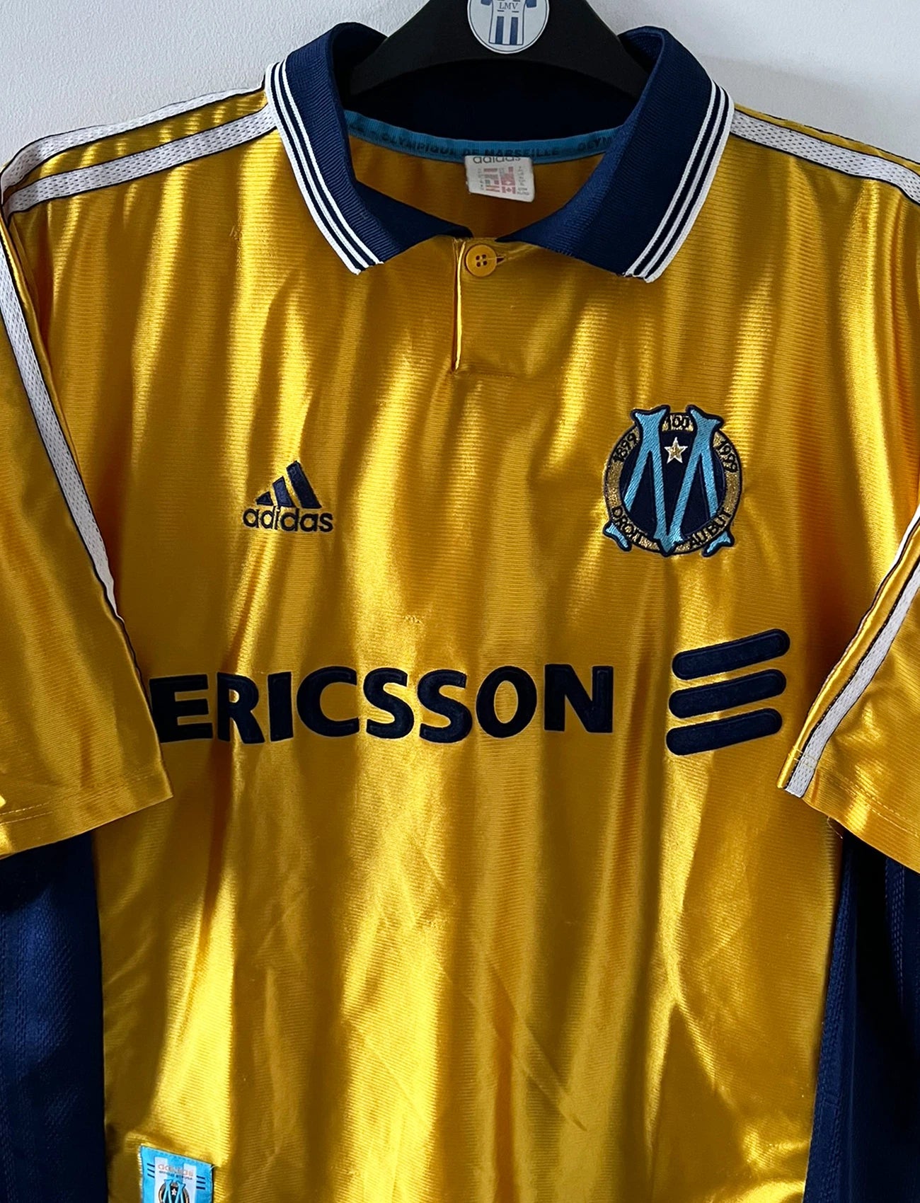 Maillot de foot vintage third doré de l'om 1998/1999. On peut retrouver l'équipementier Adidas et le sponsor Ericsson. Il s'agit d'un maillot authentique d'époque.
