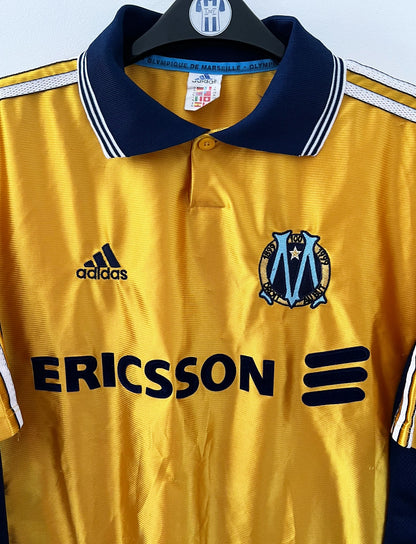 Maillot de foot vintage third doré de l'OM 1998/1999. On peut retrouver l'équipementier Adidas et le sponsor Ericsson. Il s'agit d'un maillot authentique d'époque.