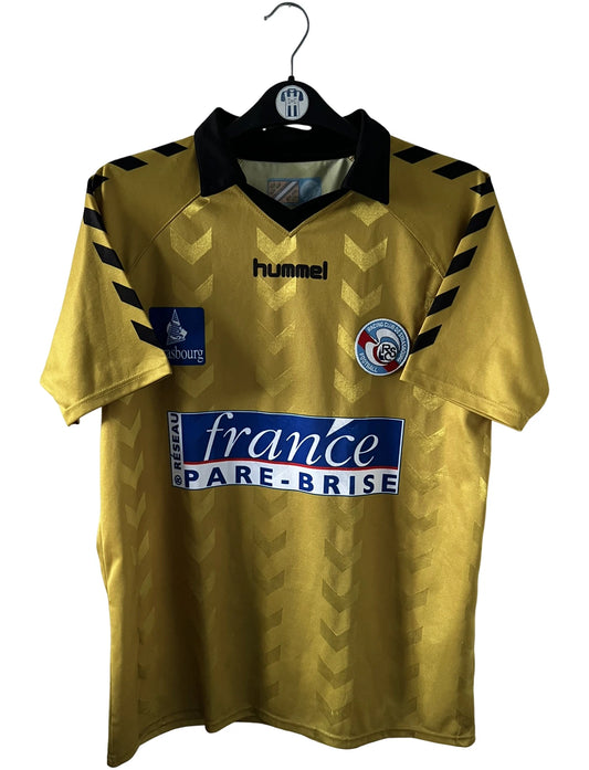 Maillot de foot vintage doré du Racing Club de Strasbourg 2008/2009. On peut retrouver l'équipementier Hummel et le sponsor France Pare-brise. Il s'agit d'un maillot authentique d'époque.