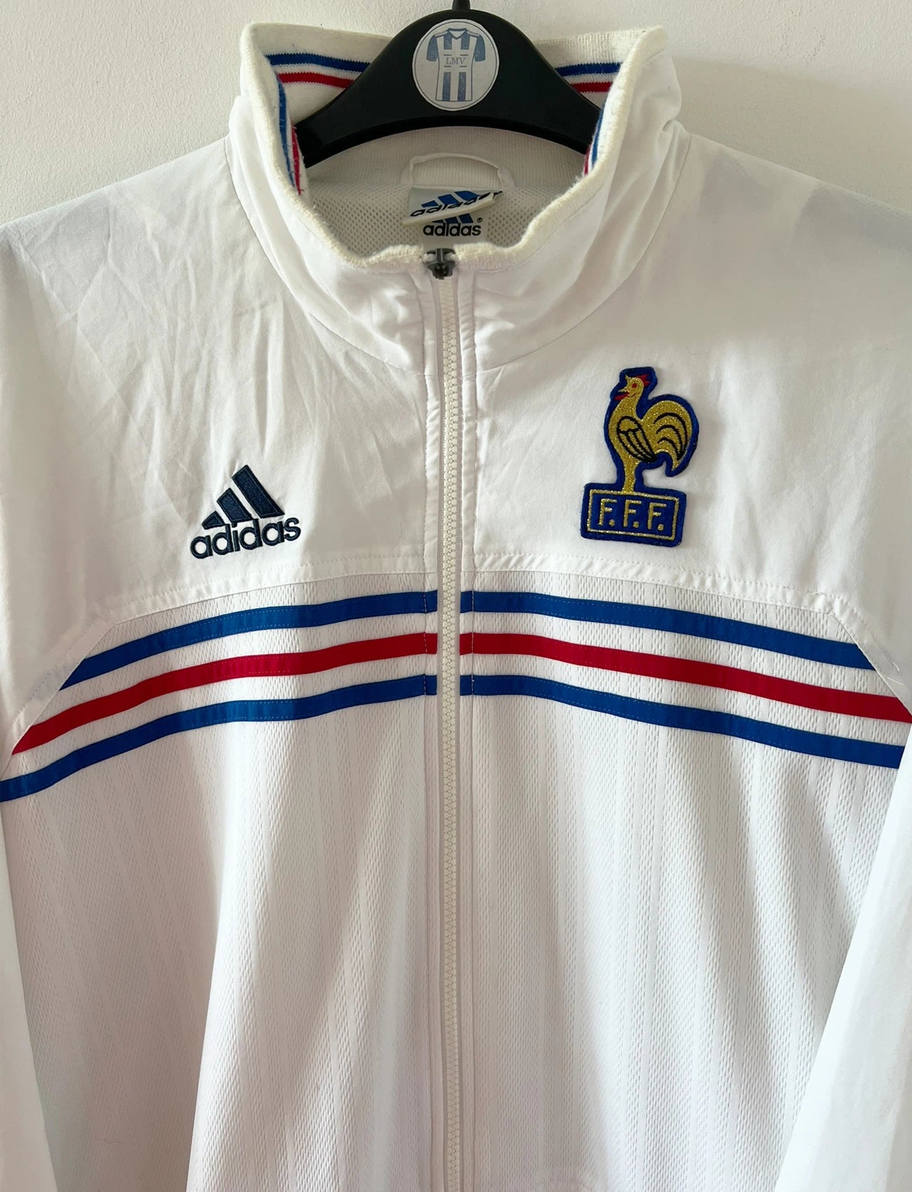 Veste de foot vintage blanche de l'Equipe de France 1998. On peut retrouver l'équipementier Adidas. Il s'agit d'une veste authentique d'époque.
