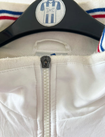 Veste de foot vintage blanche de l'Equipe de France 1998. On peut retrouver l'équipementier Adidas. Il s'agit d'une veste authentique d'époque.