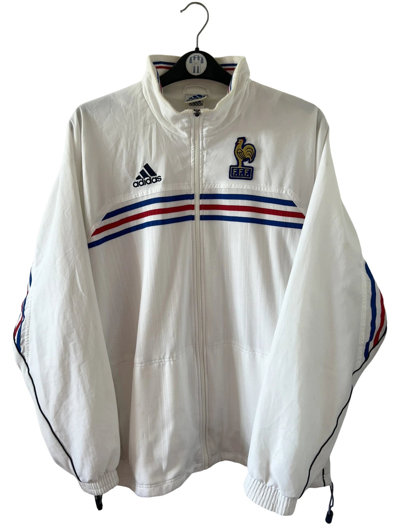 Veste de foot vintage blanche de l'Equipe de France 1998. On peut retrouver l'équipementier Adidas. Il s'agit d'une veste authentique d'époque.