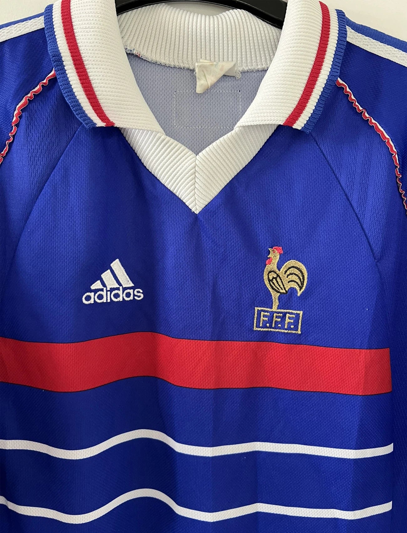 Maillot de foot vintage bleu, blanc et rouge de l'équipe de france 1998. On peut retrouver l'équipementier adidas. Il s'agit d'un maillot authentique édité avant la finale de la coupe du monde car celui-ci ne possède pas l'étoile.