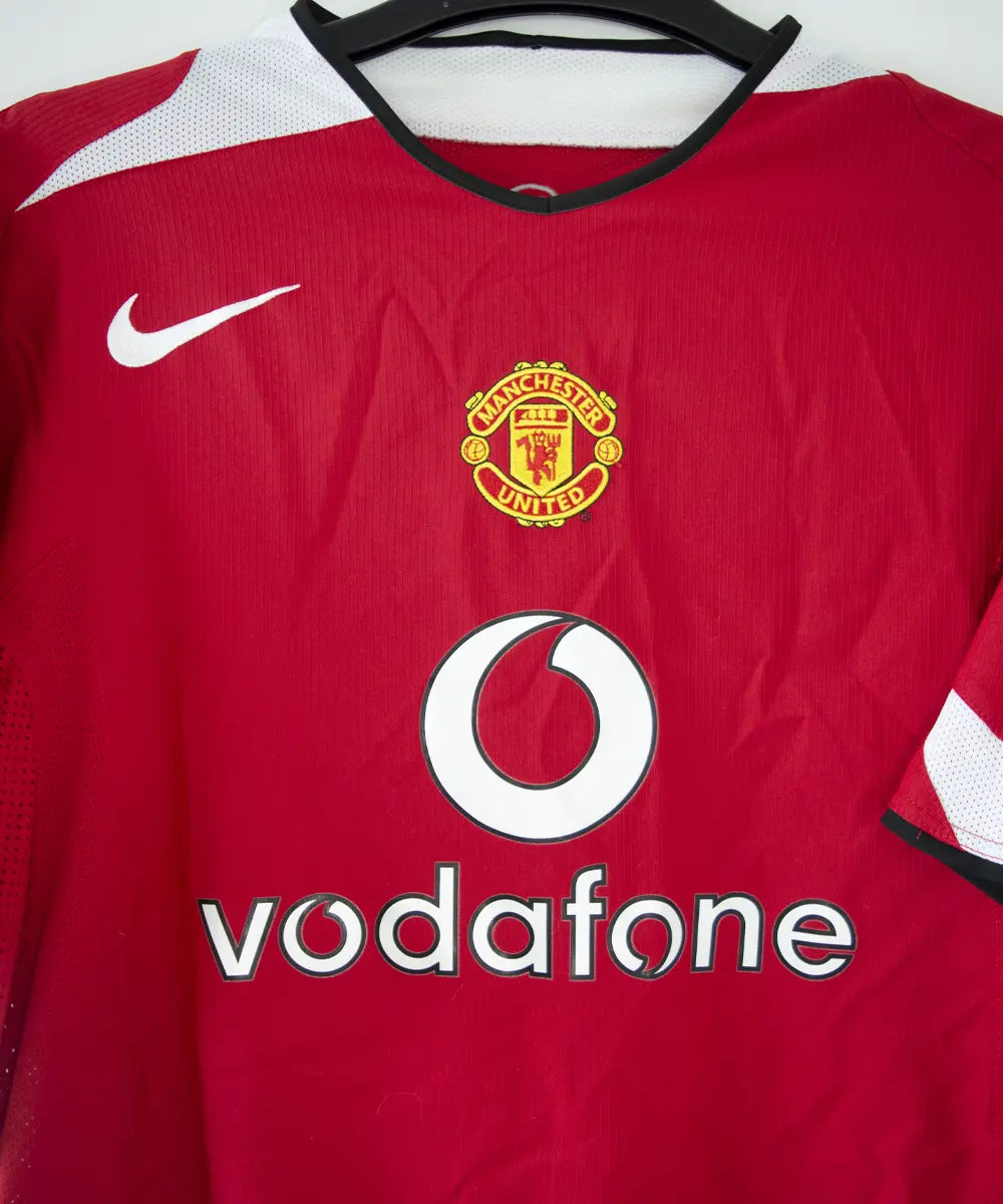 Maillot domicile de manchester united rouge, blanc et noir, édité lors de la saison 2004-2005 et la saison 2005-2006. On peut retrouver l'équipementier nike et le sponsor vodafone.