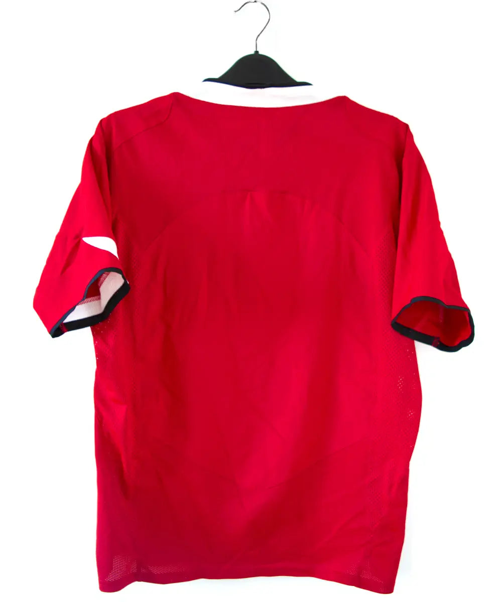 Maillot domicile de manchester united rouge, blanc et noir, édité lors de la saison 2004-2005 et la saison 2005-2006. On peut retrouver l'équipementier nike et le sponsor vodafone.